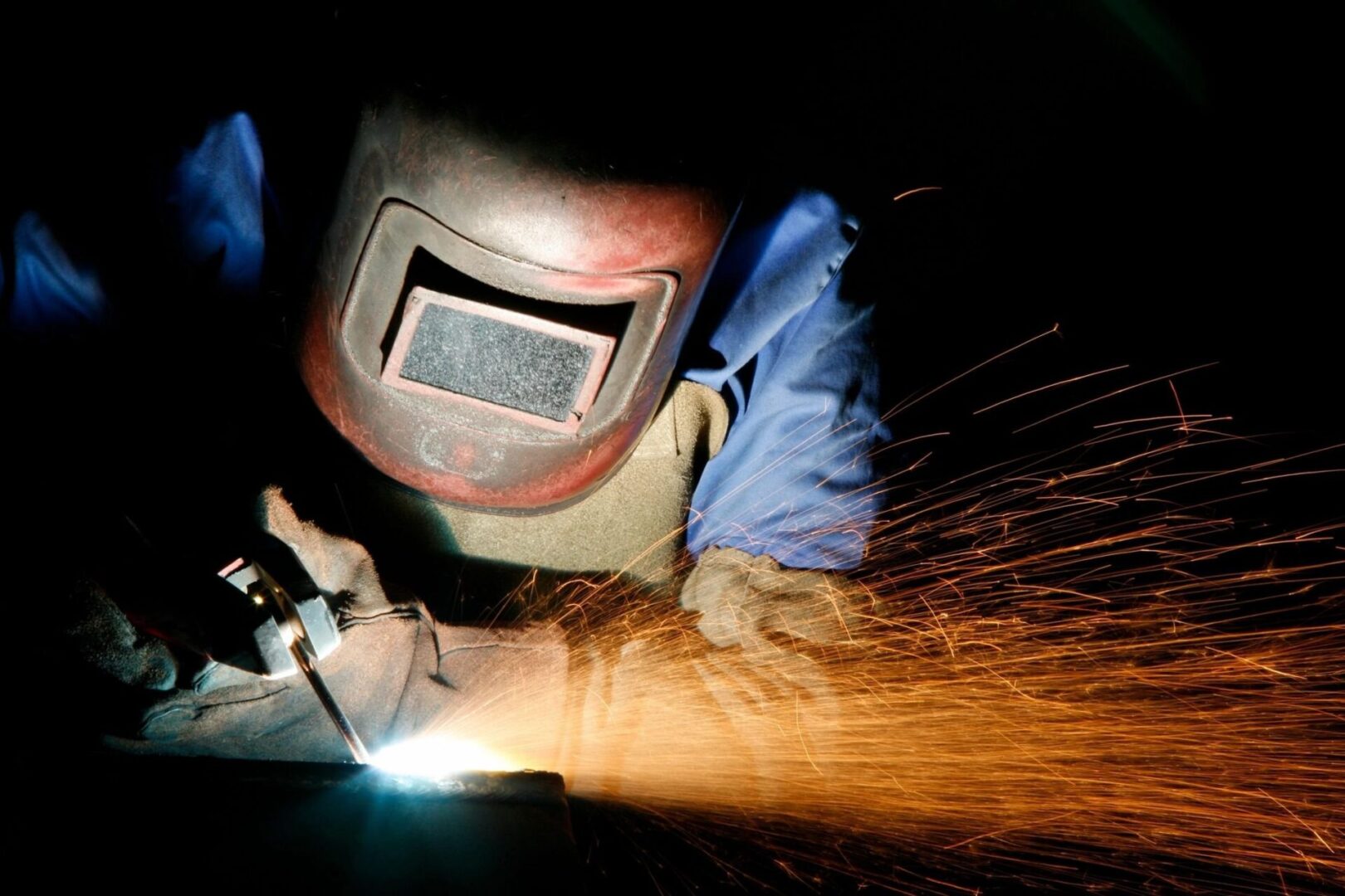 A person wearing protective gear welding metal.