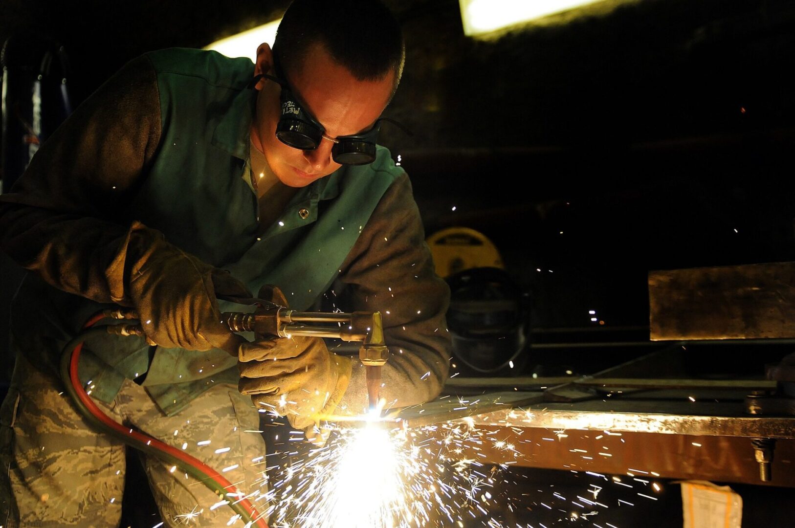 A man wearing safety glasses and working with metal.